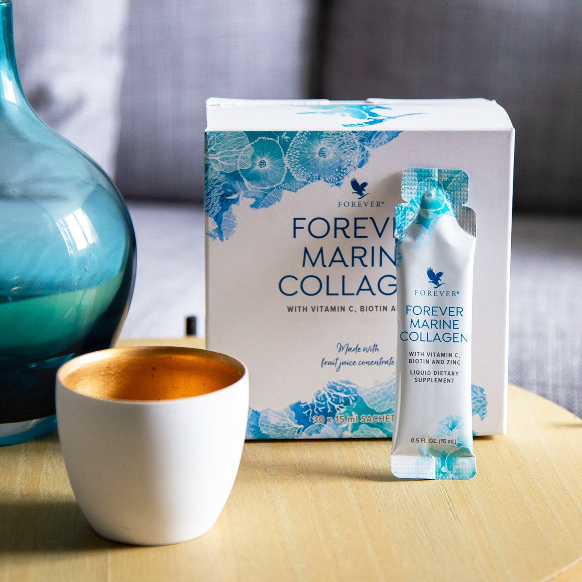Forever Marine Collagen-box och färdigshot placerade på bord tillsammans med kopp och dekorativ vas.