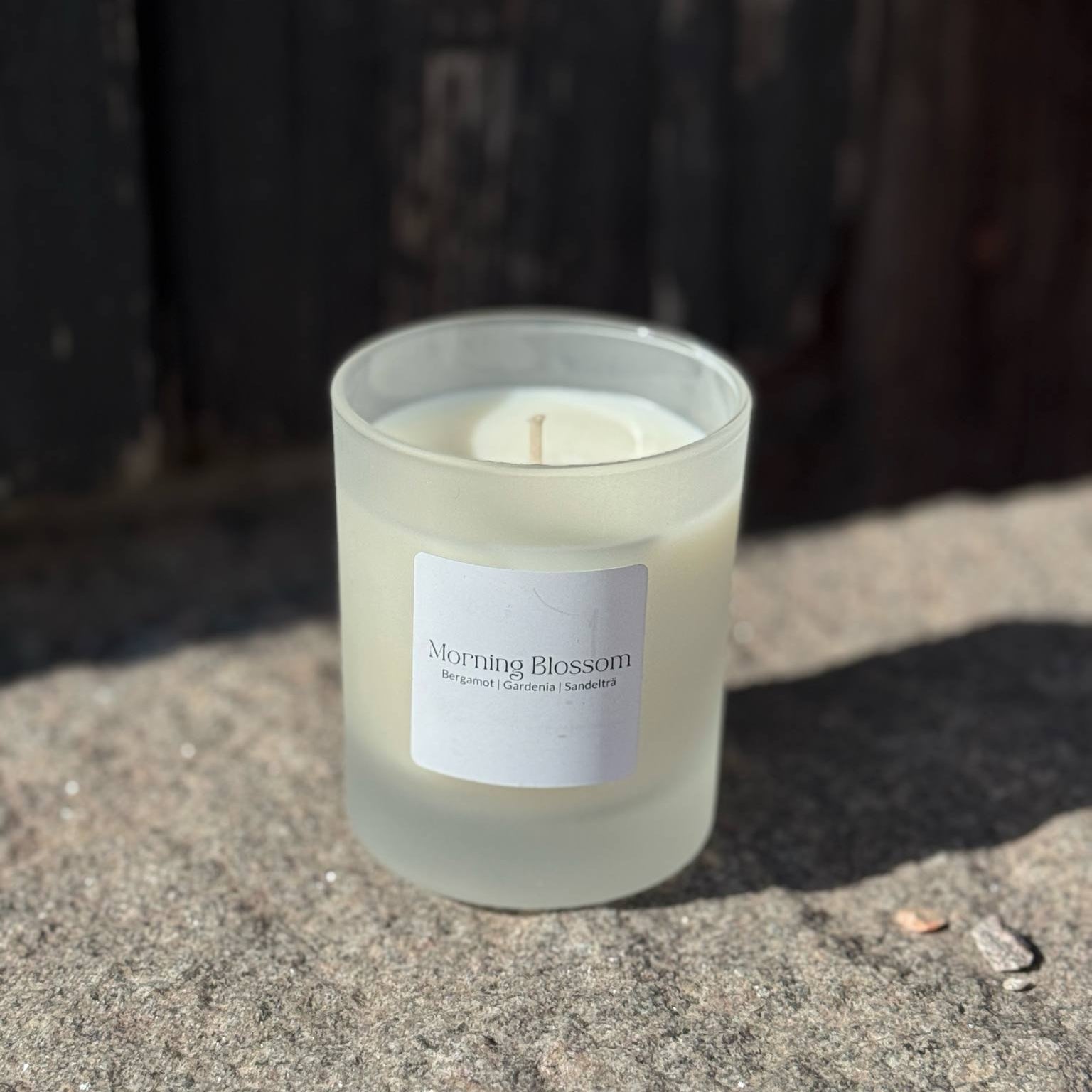 Doftljuset Morning Blossom i frostat glas stående på sten med mörkt trä i bakgrunden.