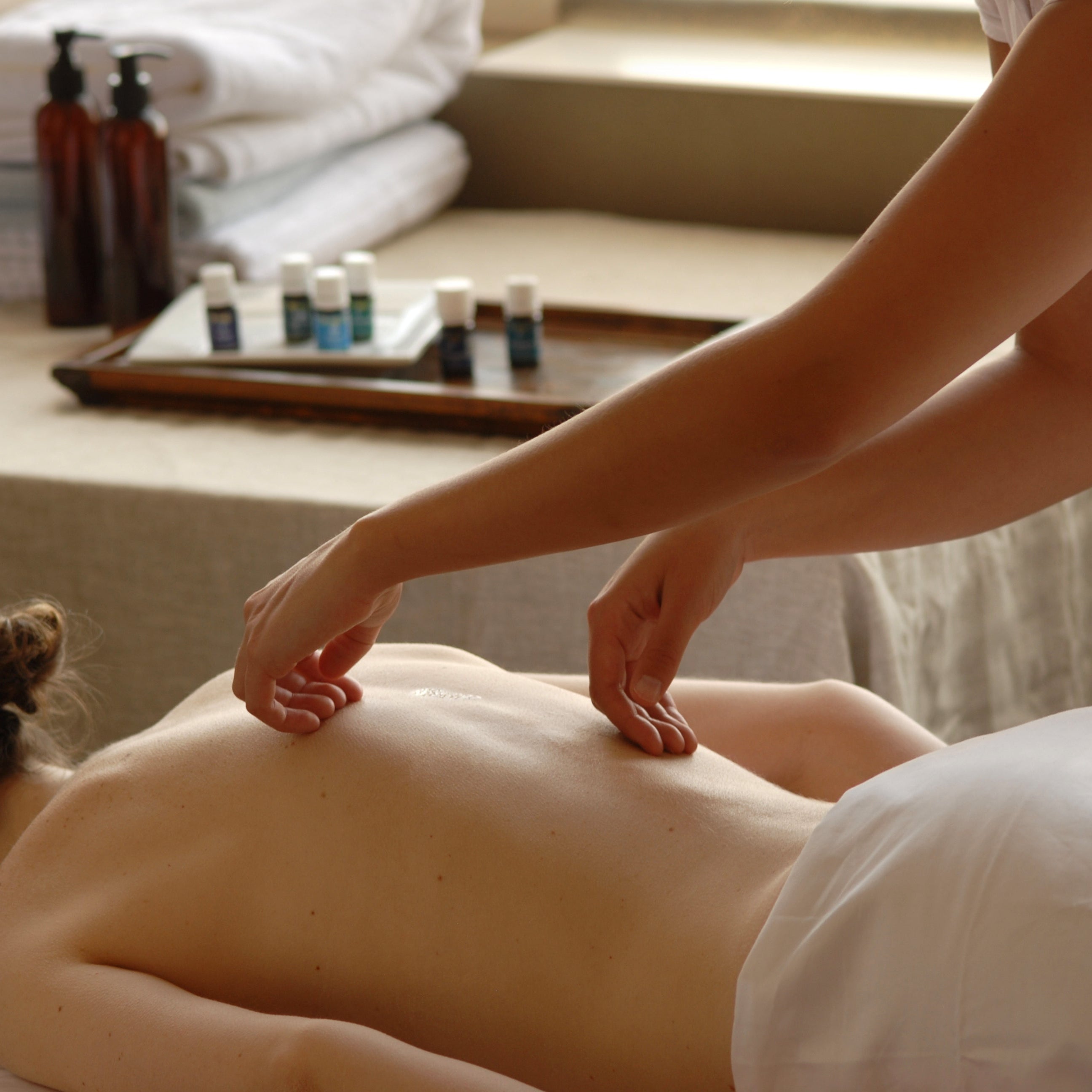 Regndroppsmassage på rygg där eteriska oljor droppas längs ryggraden och masseras in med mjuka strykningar.